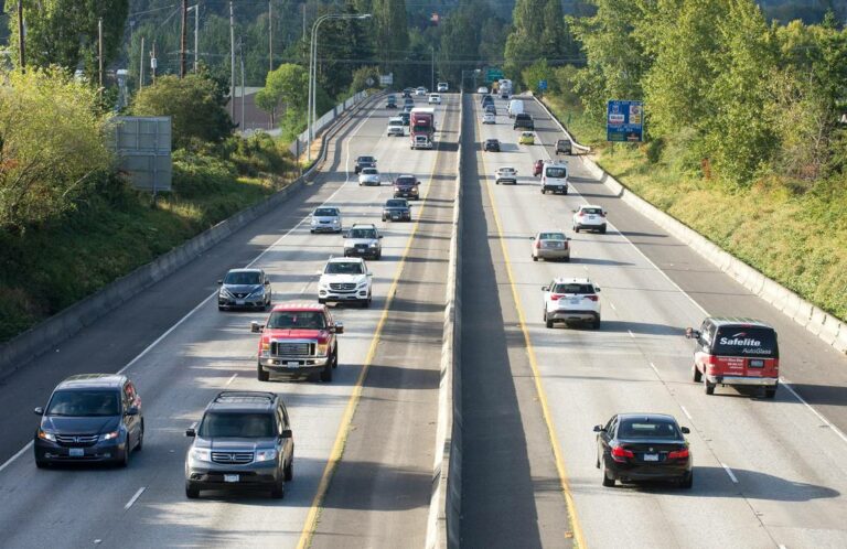 Busy highway scene with various cars and trucks traveling in both directions