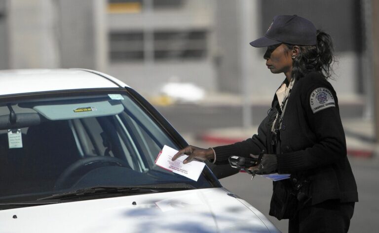 A traffic officer places a parking violation notice on the windshield of a white car