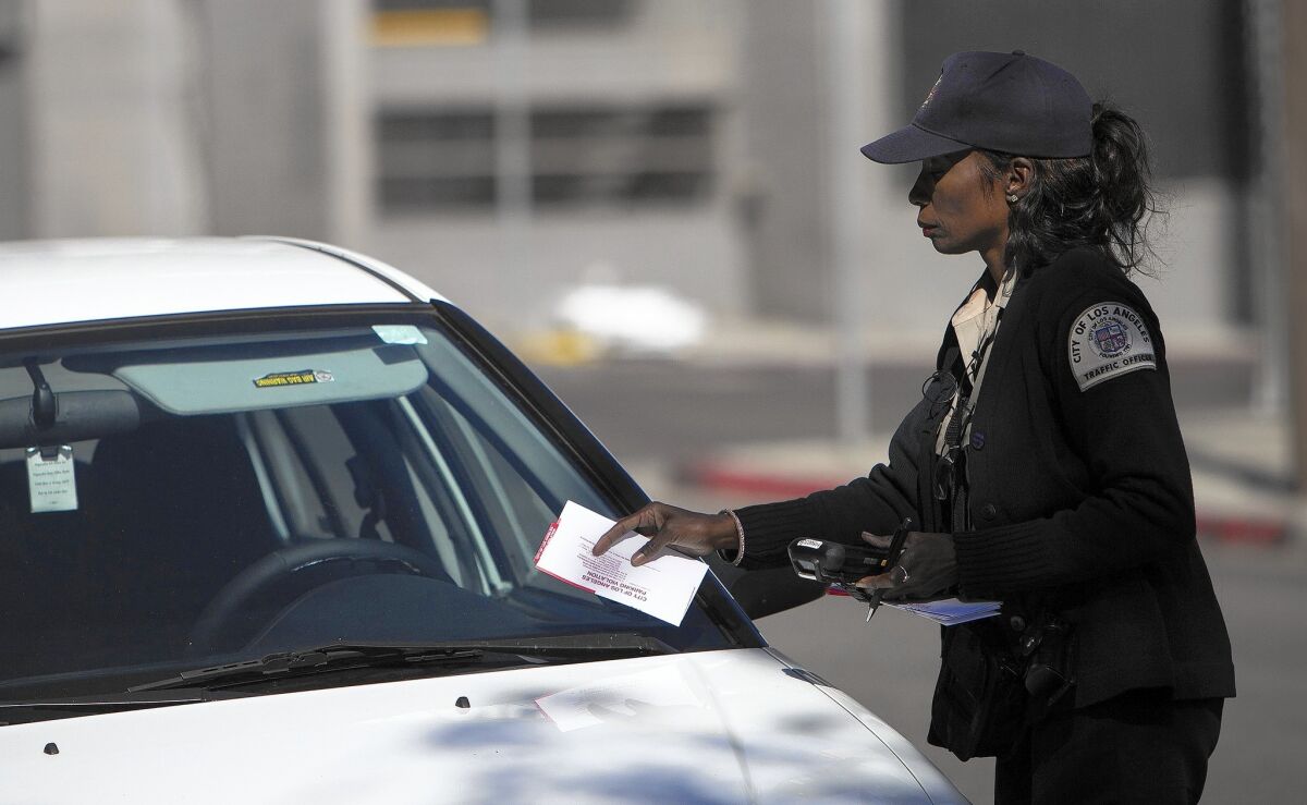 A traffic officer places a parking violation notice on the windshield of a white car